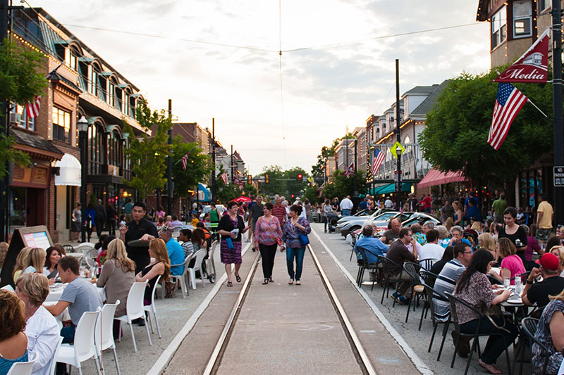 Busy downtown Media, PA street in the evening with people sitting at tables enjoying their meals