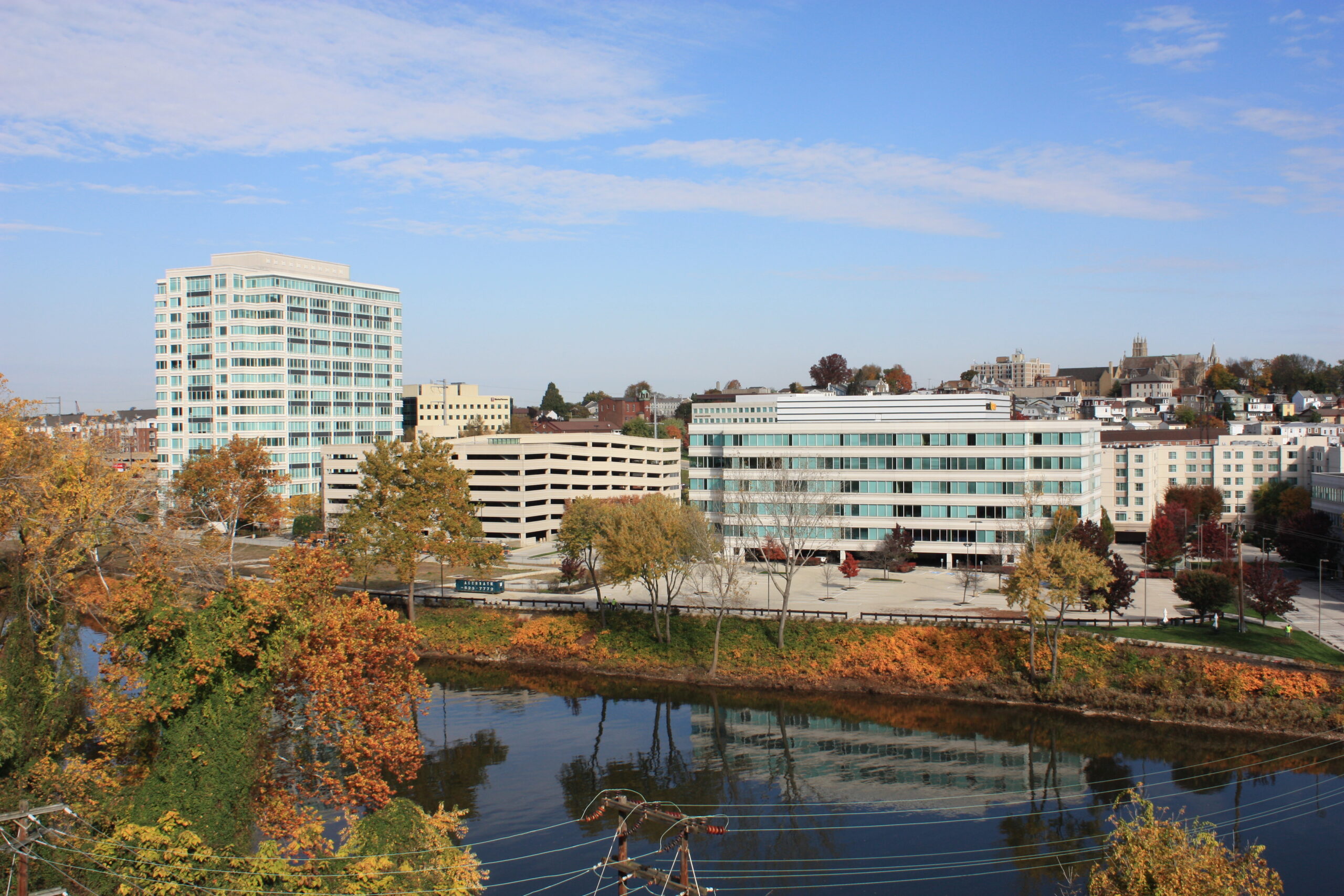 Aerial view of Conshocken riverfront  business district with modern office buildings, autumn foliage, and a calm river.