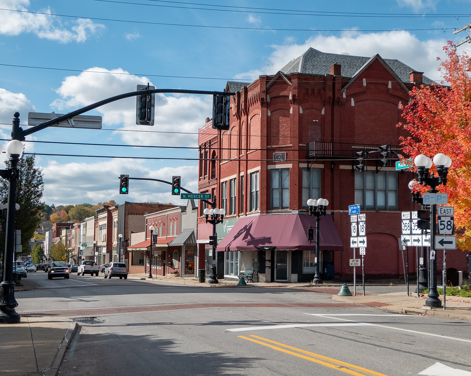 Downtown Main Street in Greenville, Pennsylvania, with historic brick storefronts, parked cars, and small-town businesses lining the street.
